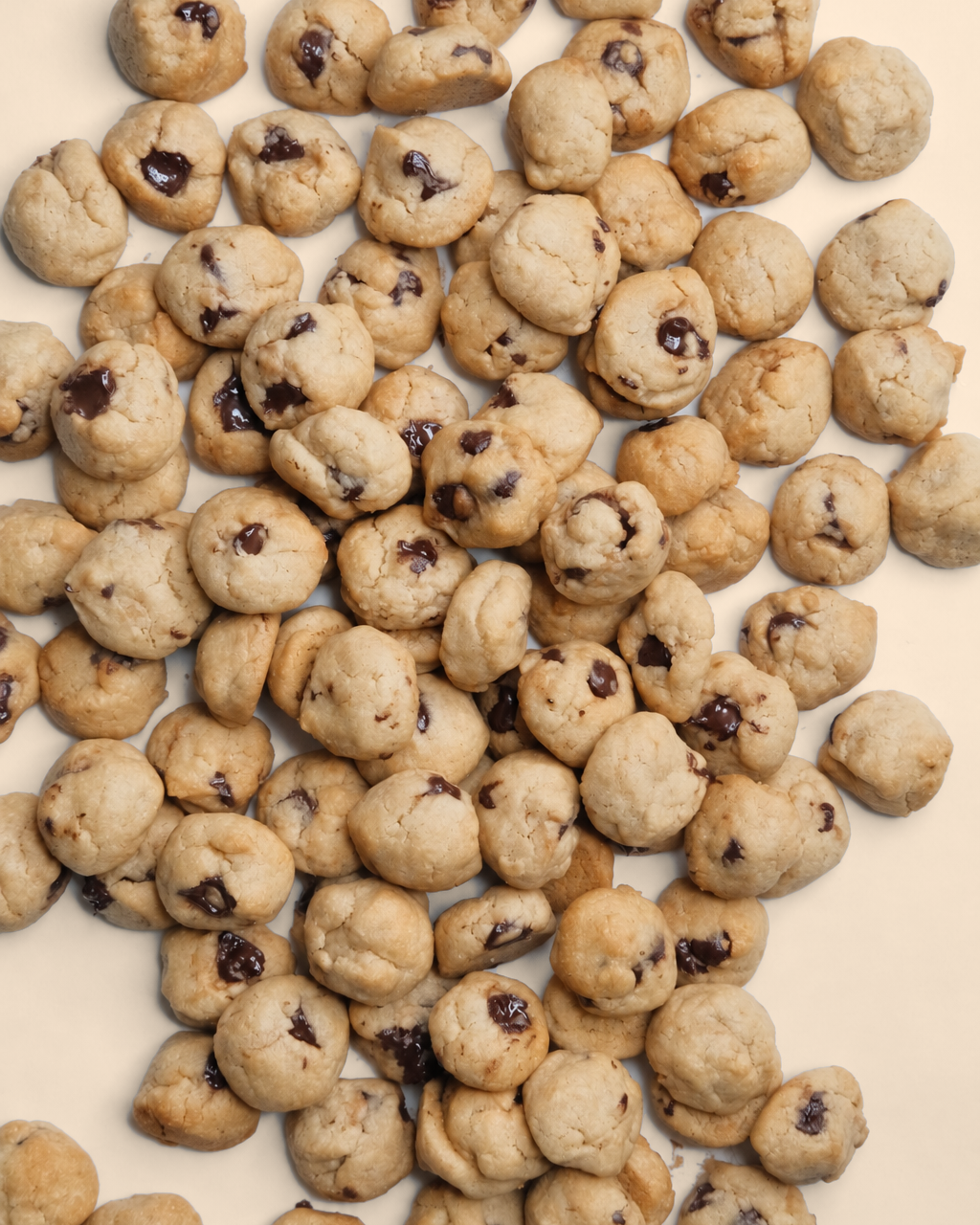 Mini blys bites with dark chocolate chips scattered on a cream surface