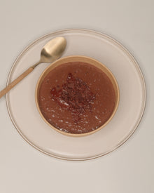A single TSCS bowl on a ceramic plate beside a spoon